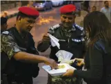  ?? — AFP ?? A protester offers sweets to police officers during a demonstrat­ion in Amman.