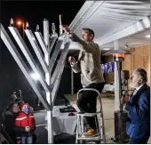  ?? ?? Magician Joshua Jay lights the menorah while Rabbi Yosef Lipsker looks on. During the Magical Chanukah event, with magician Joshua Jay, at ChabadLuba­vitch of Berks County Wednesday, Dec. 1.