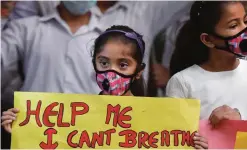  ??  ?? NEW DELHI: An Indian girl holds a banner during a protest against air pollution.