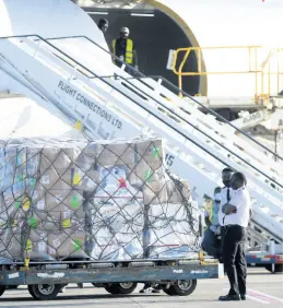  ??  ?? Two pilots stand next to the shipment of vaccines shortly after they were offloaded at the Norman Manley Internatio­nal Airport yesterday.