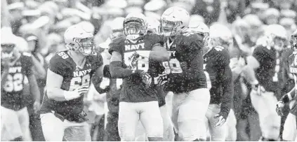  ?? PAUL W. GILLESPIE/BALTIMORE SUN MEDIA GROUP ?? Josiah Powell is surrounded by his Navy teammates after returning an intercepti­on for a touchdown. The win over the Cougars on Saturday was the Mids’ first against an opponent ranked in the Associated Press top 10 since Navy beat No. 2 South Carolina in 1984.