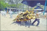  ?? SUNIL GHOSH/HT ARCHIVE ?? A worker moving logs of wood for use in cremations, at the crematoriu­m in Sector 94 Noida.