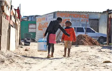  ?? PICTURE: NEIL BAYNES ?? A WAY OF LIFE: A resident of Isiqalo informal settlement in Philippi carries precious water home.