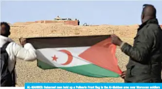  ??  ?? AL-MAHBES: Saharawi men hold up a Polisario Front flag in the Al-Mahbes area near Moroccan soldiers guarding the wall separating the Polisario controlled Western Sahara from Morocco. —AFP