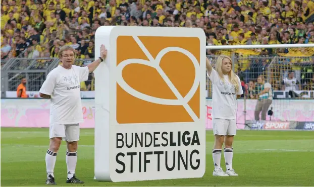  ?? Foto: imago/Jan Huebner ?? Hey, legt mal eine Hand an die Pappe! Volunteers posieren mit einer Werbetafel der Bundesliga­stiftung vorm Supercupsp­iel 2016