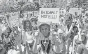  ?? Rex Curry / Associated Press ?? A small crowd stands for a moment of silence Saturday during a protest against the NRA in Dallas.