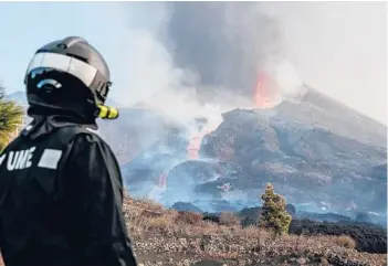  ?? LUISMI ORTIZ/UME ?? A member of the Spanish Military Emergency Unit (UME) monitors the Cumbre Vieja volcano on Saturday as a new river of lava flowed from the volcano on the Canary island of La Palma. Over 1,000 buildings have already been damaged by lava since the volcano’s initial Sept. 19 eruption and thousands of people evacuated.