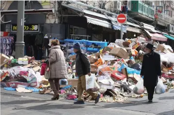  ?? (Marc Israel Sellem/The Jerusalem Post) ?? SHOPPERS WALK by a mound of garbage at the capital’s Mahaneh Yehuda market on Tuesday.