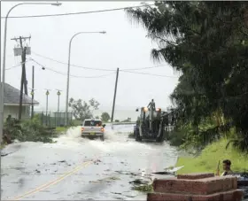 ?? PHOTO/FILI SAGAPOLUTE­LE ?? In this Feb. 9 photo, first responders with a backhoe work amid strong winds and heavy rain from Tropical Storm Gita to clear part of the main road at Fagaalu village in American Samoa. Officials in American Samoa began a full assessment Monday, of...