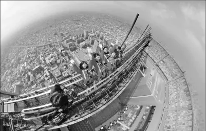  ?? KYODO NEWS VIA GETTY IMAGES ?? College students experience a thrilling walk at the top of the 300-meter-high Abeno Harukasu building in Osaka on Wednesday, a week ahead of the official opening of the “Edge the Harukasu” attraction at Japan’s tallest building.