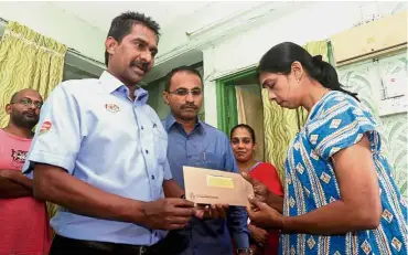  ??  ?? Condolence­s: Anthony handing over a cheque to Shanti at her home in Taman Tun Sardon, Gelugor, Penang.