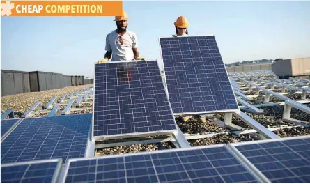  ?? — Reuters ?? Employees of Sunedison install photovolta­ic solar panels on the roof of a Kohl’s Department Store in Missouri.