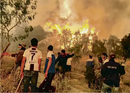  ?? ABDELAZIZ BOUMZAR / REUTERS ?? Veïns d’un poble proper a Tizi-Uzu proven d’aturar l’avanç de les flames