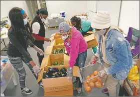  ??  ?? Jones (left) works with volunteers organizing food for distributi­on in Miami.