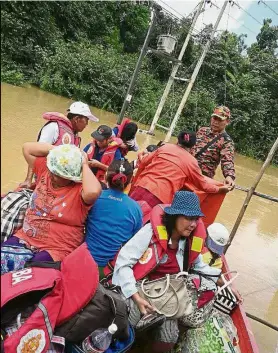  ??  ?? Fleeing to safety: Fire and Rescue Department personnel evacuating flood victims in Stapang.