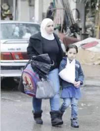  ?? — AFP ?? A Syrian woman and a student head to school following days of calm in Damascus’s Old City.