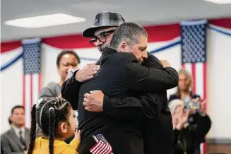 ?? Gregory Bull / Associated Press ?? Deported veterans Mauricio Hernandez Mata, center right, and Leonel Contreras embrace after being sworn in as U.S. citizens at a special naturaliza­tion ceremony Wednesday in San Diego. Both Army veterans, the two men were among 65 who were allowed back into the United States nearly a year ago as part of a growing effort by the U.S. government to recognize the service of immigrants who served in the U.S. military only to wind up deported.