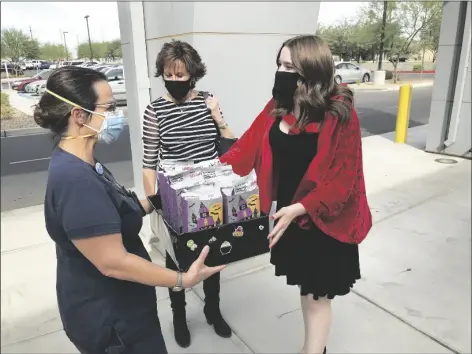  ??  ?? ABOVE: Dressed as Little Red Riding Hood, Gila Ridge Senior Sydney Williams (right) is delivering a box of goodie bags Friday at Yuma Regional Medical Center to nurse Darci Holoboff (left) be given to children in the pediatrics unit for Halloween. After having done it as a child for several years she wanted to do it one last time before heading off to college. William’s mother Sharon is in the background.