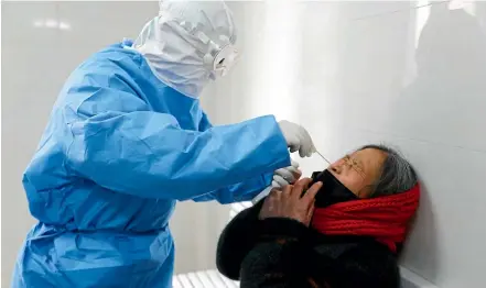  ?? AP ?? A doctor takes a swab from a woman to test for the COVID-19 virus at a fever clinic in Yinan county in eastern China’s Shandong province.