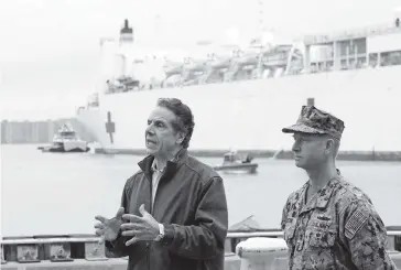  ?? KATHY WILLENS AP ?? New York Gov. Andrew Cuomo, left, stands near the USNS Comfort, a naval hospital ship that has a 1,000-bed capacity and arrived Monday in New York. The ship will treat non-COVID-19 patients as the city’s hospitals fill up with COVID-19 patients.