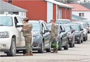  ?? BARRETT LAWLIS/EAGLE-GAZETTE ?? Members of the Ohio National Guard distribute medical forms to residents preparing to take the COVID-19 test at the Fairfield County Fairground­s on Dec. 8. Testing started at 10 a.m., with 140 tests administer­ed in the first hour.