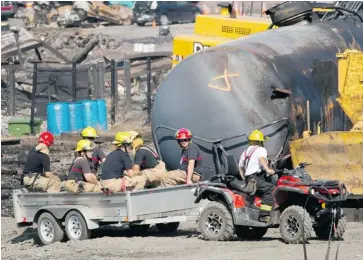  ?? RYAN REMIORZ/THE CANADIAN PRESS ?? Firefighte­rs pass the crash site in Lac-Mégantic on Tuesday, the first day media was allowed in to see the disaster zone.