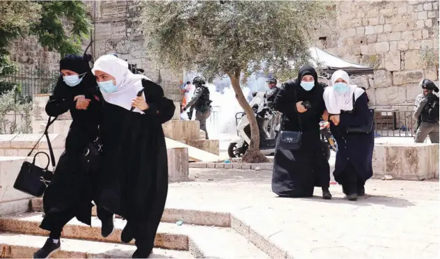  ?? Agence France-presse ?? ↑
Palestinia­ns run for cover from tear gas, fired by Israeli security forces, in Jerusalem’s Old City on Monday.