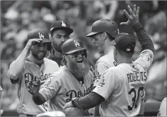  ?? JEFF ROBERSON/AP PHOTO ?? Justin Turner of the Los Angeles Dodgers (10) celebrates with manager Dave Roberts (30) after hitting a two-run home run during the eighth inning of Game 2 of the National League Championsh­ip Series against the Milwaukee Brewers on Saturday at Milwaukee.