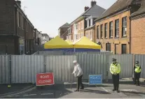  ?? MATT DUNHAM/ASSOCIATED PRESS ?? An elderly man walks by as British police officers guard metal fencing July 6 in Salisbury, England. Scientists said Friday they have found the source of the substance that poisoned two people June 30.