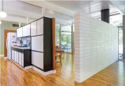  ??  ?? BELOW: THIS THREE-QUARTER WALL IS ONE OF ZANN’S FAVORITE ARCHITECTU­RAL ELEMENTS, PROVIDING SEPARATION BETWEEN THE EATING AND LIVING SPACES BUT ALSO LETTING LIGHT FLOOD IN THROUGHOUT. BOTTOM: MOST OF THE KITCHEN WAS INTACT WHEN ZANN AND JEFF MOVED IN. IT FEATURES THE ORIGINAL CABINETRY AND THERMADOR OVEN AND COOKTOP. THE STOVE-SIDE COUNTERTOP RETAINS ITS ORIGINAL FORMICA COUNTERTOP.