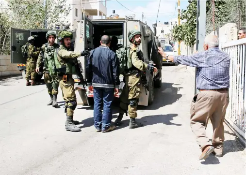  ??  ?? A Palestinia­n man argues with Israeli soldiers as they arrest the brother of Nimr Jamal near Ramallah on Tuesday. Jamal was earlier shot dead by Israelis in an illegal settlement outside Jerusalem. (Reuters)
