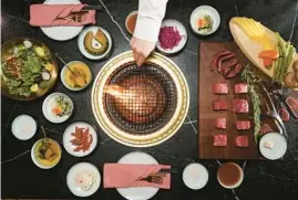  ?? JOHN J. KIM/CHICAGO TRIBUNE ?? Owner Jason Song prepares the grill for the meat paradise platter, a variety of meats, salad, soup and vegetables, at Holu on South Jefferson Street.