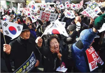  ?? JUNG YEON-JE/AFP ?? Supporters of South Korean President Park Geun-hye wave national flags during a rally against the impeachmen­t of the president outside the ruling Saenuri Party headquarte­rs in Seoul on Tuesday.