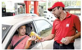  ?? ARIANA CUBILLOS/AP ?? Orlando Godoy takes a package of corn flour as payment at a gas station near Caracas.