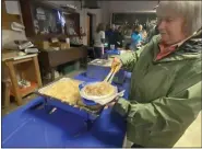  ?? ?? Sharon Reinsel of Kutztown scoops sauerkraut for her sitdown meal at Ruscombman­or Volunteer Fire Company on New Year’s Day 2022.