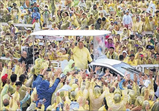  ?? DAMIR SAGOLJ / REUTERS ?? El papa Francisco, vestido con un llamativo chubasquer­o amarillo, saluda a los fieles tras la misa celebrada en Tacloban