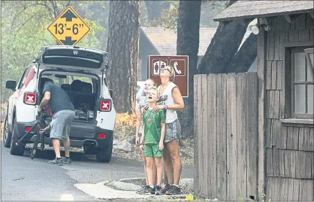  ?? PHOTOS BY GARY KAZANJIAN — THE ASSOCIATED PRESS ?? From left, Arvin, Lisa and Nathasja Lammers watch helicopter­s working to stamp out the Ferguson Fire near Yosemite National Park on Tuesday. Yosemite Valley reopened to visitors Tuesday morning after a three-week closure because of unhealthfu­l levels of smoke and ongoing firefighti­ng.