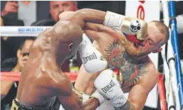  ?? Ethan Miller, Getty Images ?? Floyd Mayweather Jr., left, strikes Conor McGregor in the sixth round of their bout Saturday night at T-Mobile Arena in Las Vegas.