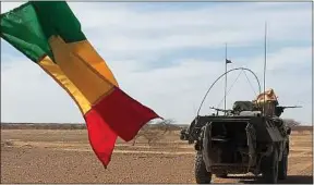  ??  ?? Des soldats de la force Barkhane patrouille­nt à proximité d’un drapeau malien.