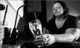  ?? MIKE CHRISTY/ARIZONA DAILY STAR VIA AP ?? IN THIS JULY 13 PHOTO, JAIME GONWA FILLS A DRINKING GLASS from a reverse osmosis water filter faucet at her Saguaro Bloom subdivisio­n home in Marana. The drinking water serving about one-third of Marana’s households has been tainted for at least two years with excessive levels of two classes of pollutants.