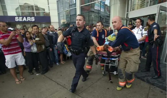  ?? RICK MADONIK/TORONTO STAR ?? Emergency responders rush a shooting victim to a waiting ambulance following last Saturday’s shooting at the Eaton Centre. One man was killed and several bystanders wounded.