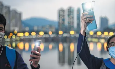  ?? Philip Fong / AFP / Getty Images ?? Students switch on the light of their mobile phones as they take part in a human chain event at Sand Martin Bridge in Sha Tin district in Hong Kong on Thursday.