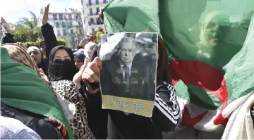  ??  ?? An Algerian protester holds a poster bearing a photo of Bensalah with slogan in Arabic and French: ‘Bensalah leave, we don’t trust you’ during an anti-system demonstrat­ion in the capital Algiers. — AFP photo