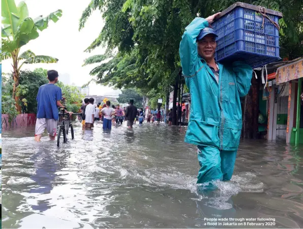  ??  ?? People wade through water following a flood in Jakarta on 8 February 2020