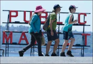  ?? (AP/Ted S. Warren) ?? People walk Tuesday near Pike Place Market in Seattle as heat moved inland after record highs were set along the Pacific Northwest coast.