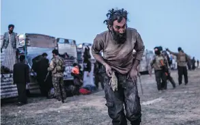  ?? BULENT KILIC / AFP / GETTY IMAGES ?? A man suspected of belonging to ISIL walks past members of the Kurdish-led SDF just after leaving ISIL’S last holdout of Baghouz on Monday.