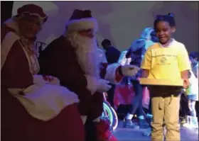  ?? KEVIN MARTIN — THE MORNING JOURNAL ?? A youngster greets Mr. and Mrs. Claus after receiving a Christmas present at the Lorain Palace Theater for Boys and Girls Clubs of Lorain County’s annual Christmas celebratio­n. Nearly 900 youngsters gathered in the 617 Broadway Ave. location for...