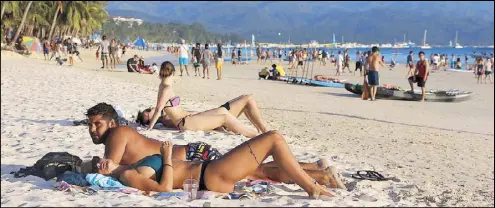  ?? AFP ?? Foreign tourists relax on the beach in Boracay on April 17 ahead of its closure. The Philippine­s is set to deploy hundreds of riot police to the top holiday island to keep travelers out and head off potential protests ahead of its six-month closure to...