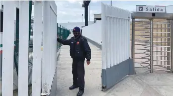  ?? (Wendy Fry/San Diego Union-Tribune/TNS) ?? FERNANDO REYES closes the gate to a foot bridge in Tijuana, Mexico, earlier this month, after the border crossing was temporaril­y shuttered in response to the coronaviru­s.