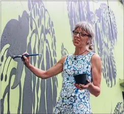  ??  ?? Huge project: Artist Kate Millington gets to work painting her kowhai flower and butterfly design onto the flyover.